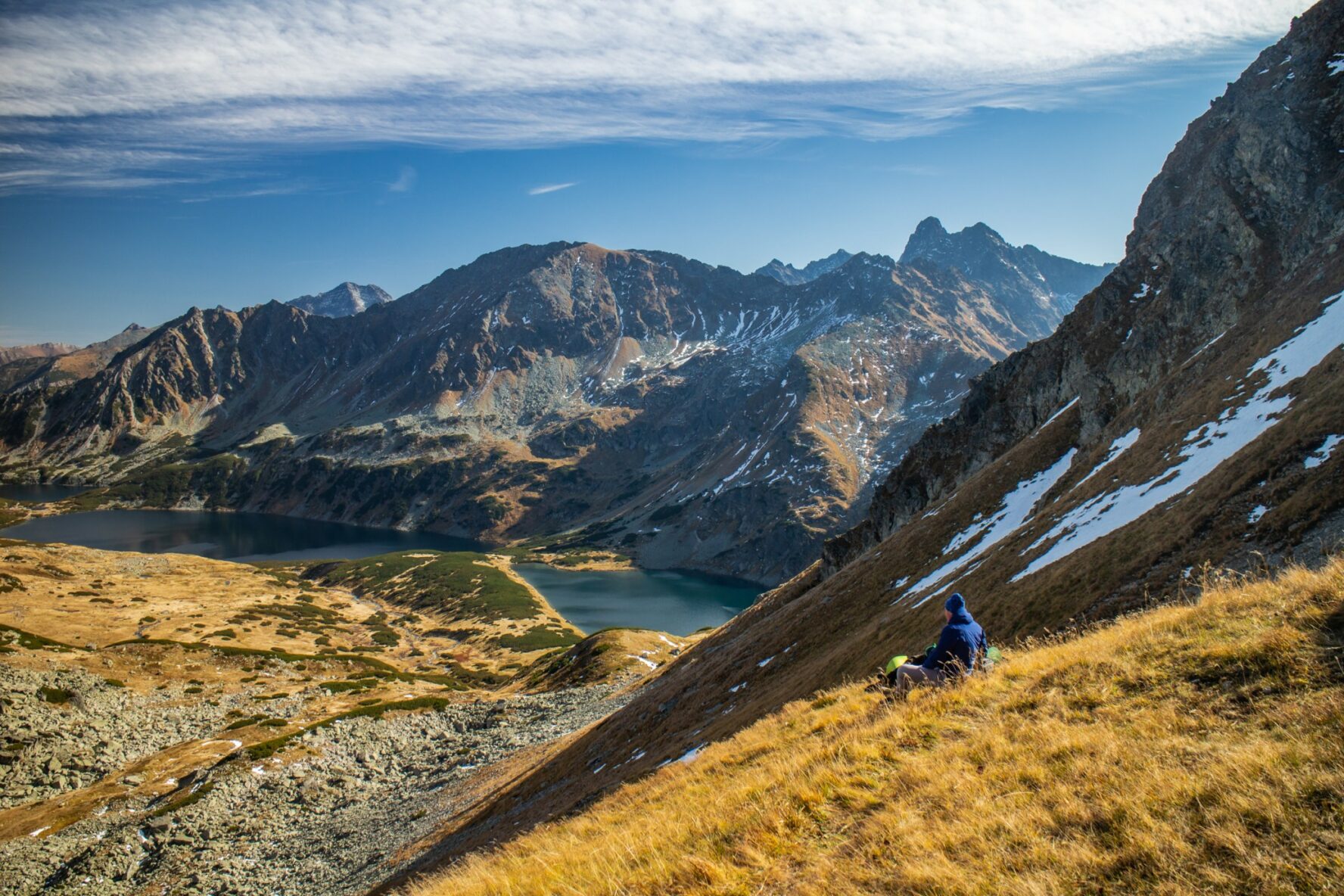 A hiker taking some rest and enjoying the views of the peaks and lake in the High Tatras, Slovakia.
