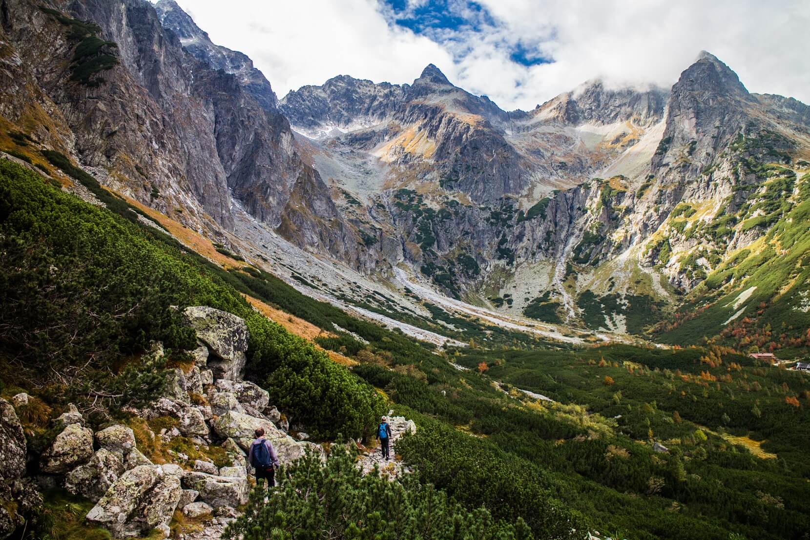 Two hikers walking along a trail surrounded by lofty peaks in the Tatras, Slovakia.