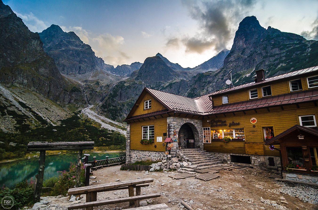 A mountain hut beside a glacial lake and surrounded by a rugged peaks in the Tatras, Slovakia.