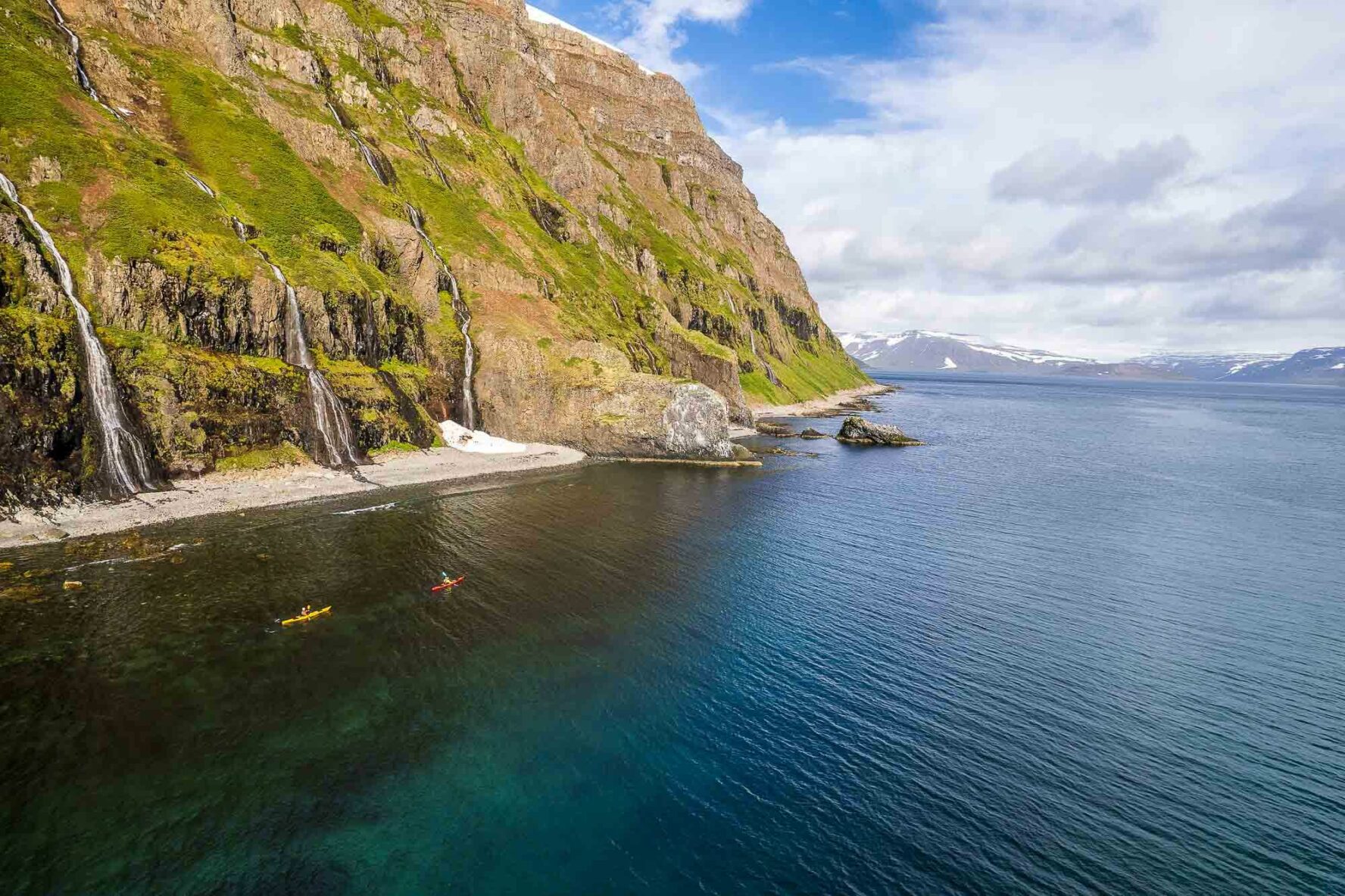 Small kayaks against steep cliffs