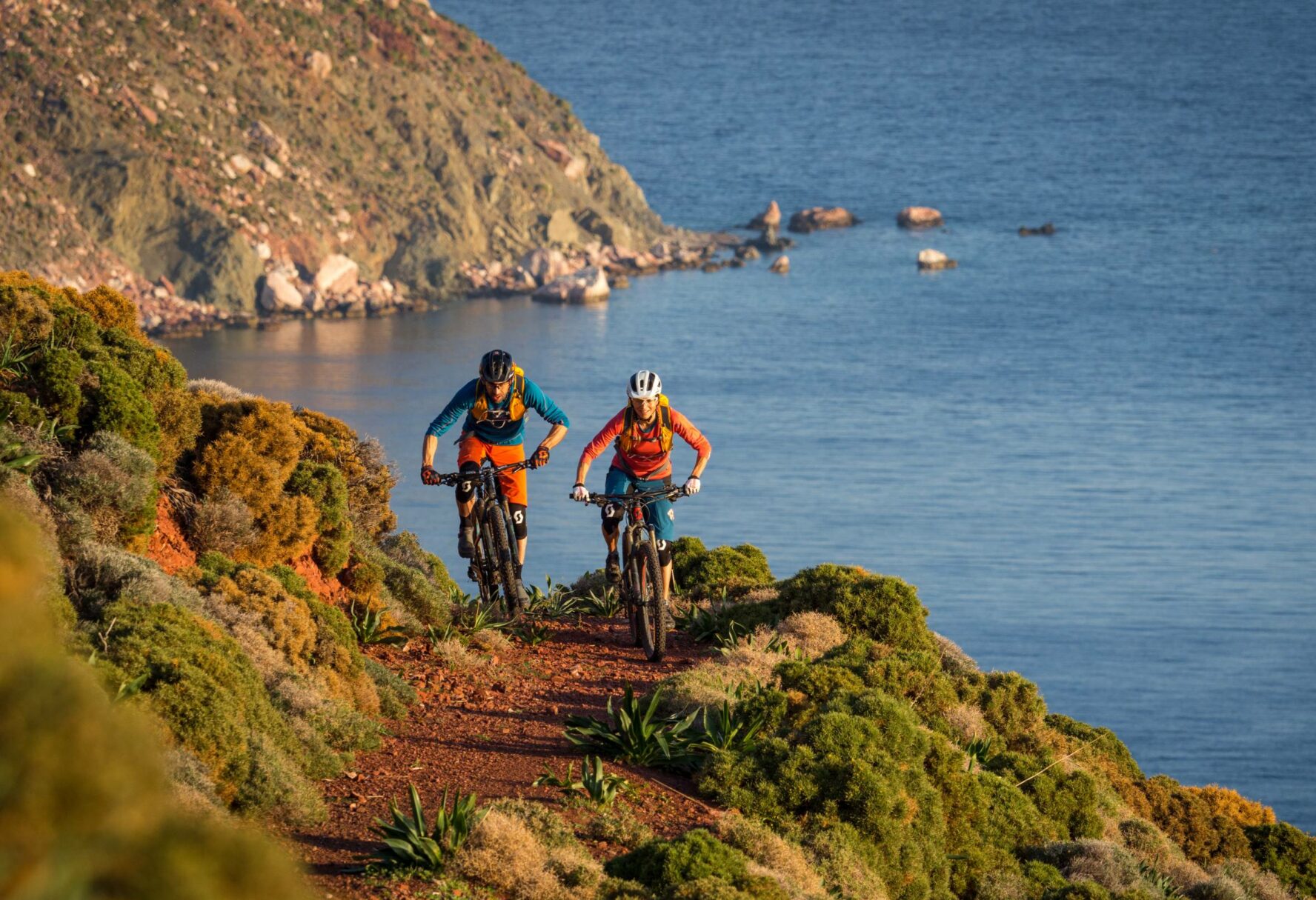 Mountain bikers riding along an MTB trail by the coast of the Greek island of Tilos.