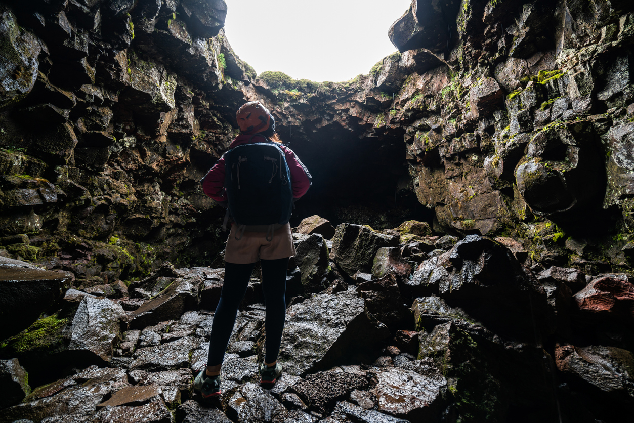 Woman traveler explore lava tunnel in Iceland. Raufarholshellir is a beautiful hidden world of cave. It is one of the longest and best-known lava tubes in Iceland, Europe for incredible adventure.