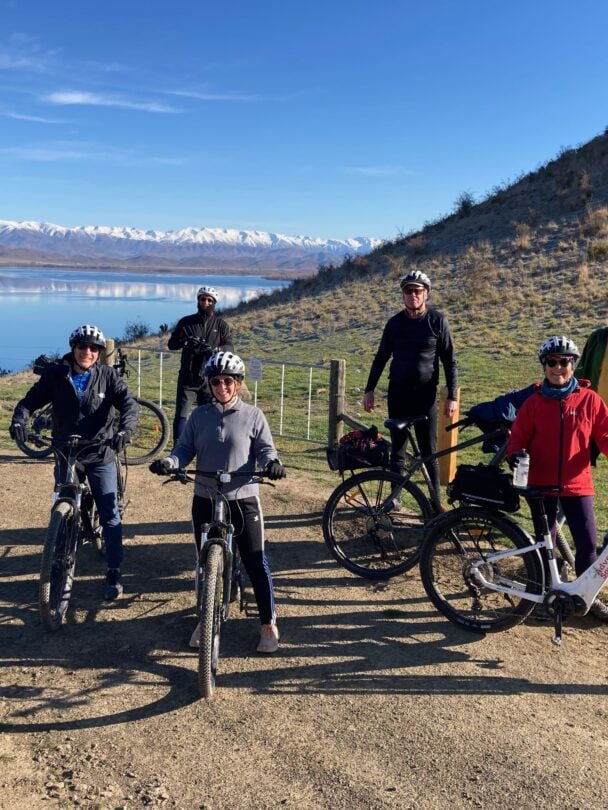 Two cyclers on a trail with mountains in the background