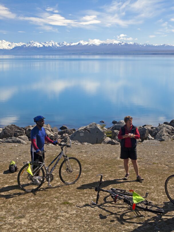 Two cyclers on a trail with mountains in the background