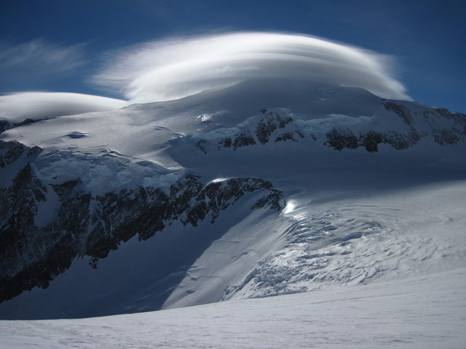 A lenticular cloud above an icy Antarctic expanse reflecting sunlight.