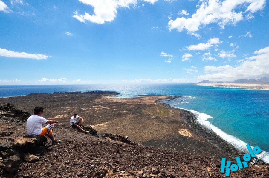 Two surfers on a hiking excursion in Lobas, taking in the views of the ocean.