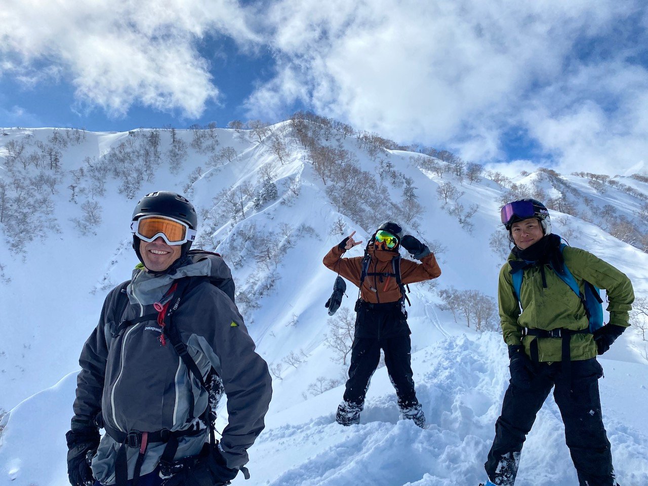 Mountain covered with snow and three skiers