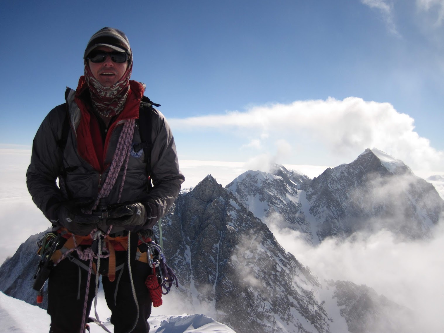 A mountaineer on the summit of Mt Vinson. Overlooking awe-inspiring Antarctic landscapes.
