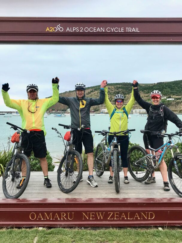 Two cyclers on a trail with mountains in the background