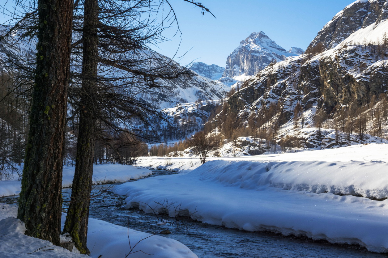 A river valley during winter surrounded by lofty peaks in Gran Paradiso National Park, Italy.