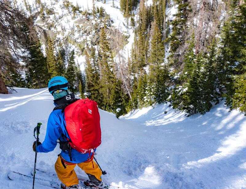 A backcountry skier standing on top of a steep slope in Colorado’s Rockies they are about to ski.