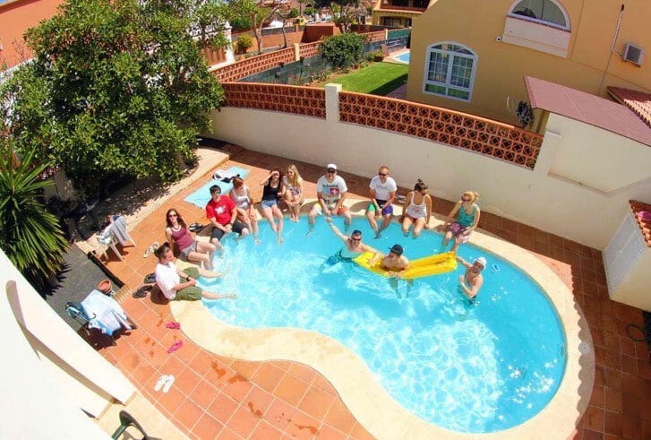 Surfers, participants of a surf school in Fuerteventura, hanging out in a kidney-shaped pool.