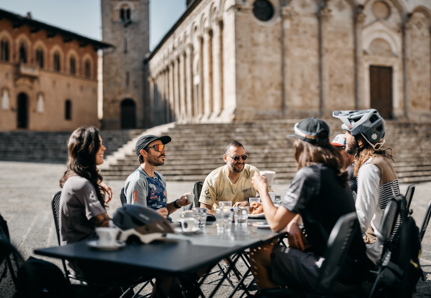 E-MTBers enjoying a breakfast with coffee and cornettos near a Romanesque church in Tuscany.