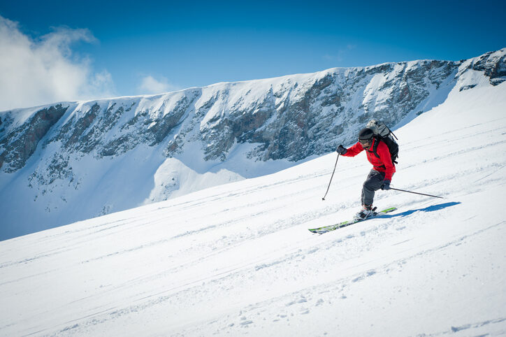 Skier going downhill in the French Alps, in the Taillefer mountain range.