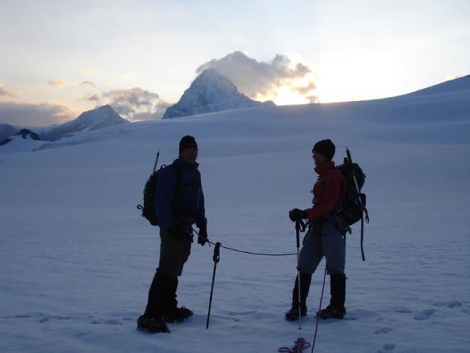 Two hikers posing for a photo while glacier trekking in the Swiss Alps, during their Haute Route traverse.