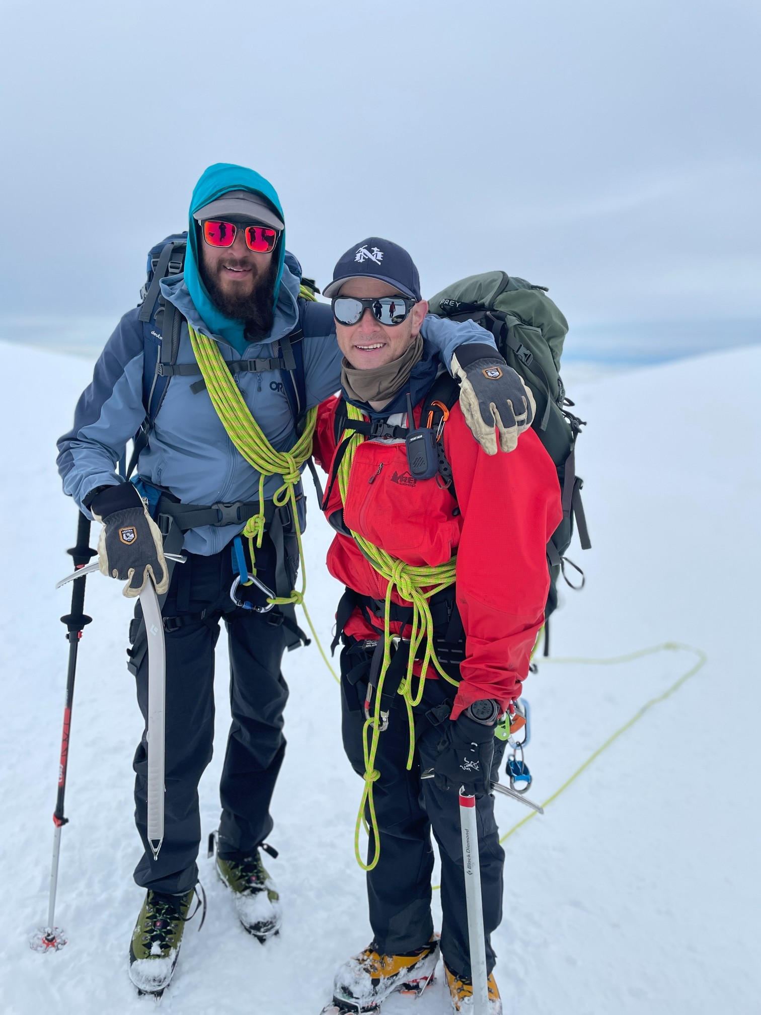 Two happy mountaineers in full gear posing for a photo on Mount Baker.