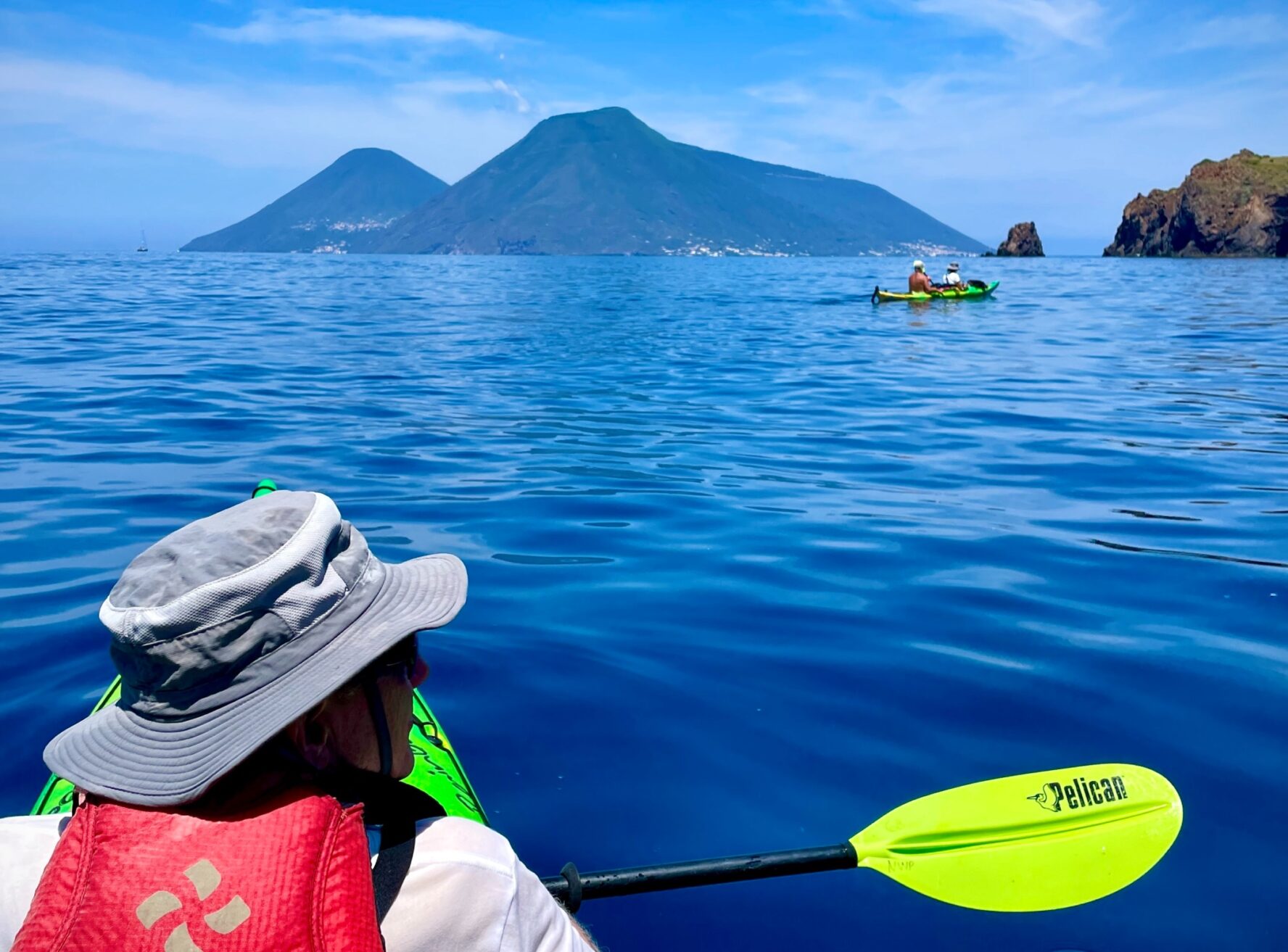 Kayakers paddling the cobalt waters in the Aeolian Islands, Italy.
