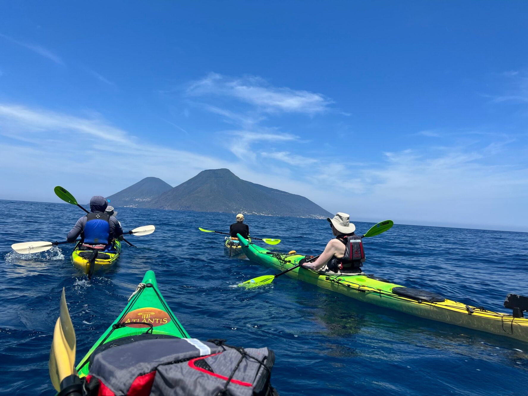 Kayakers paddling near a volcanic island, one of the Aeolian Islands, in Southern italy.