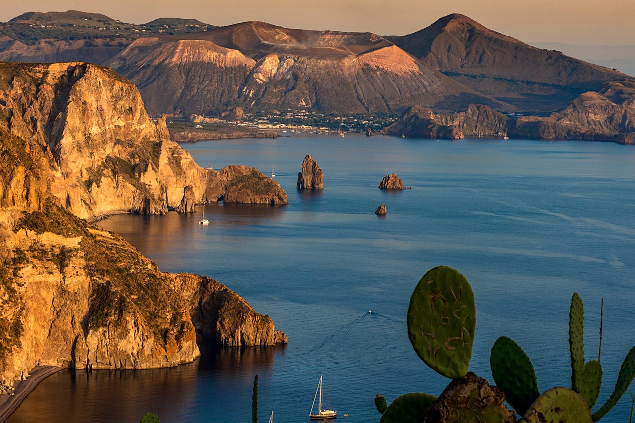 The dramatic coast of the volcanic island of Lipari, Italy, during golden hour.