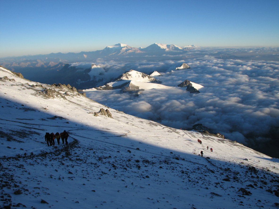 Mounatineers seen from high above, tackling winter terrain during their Aconcagua climb, above the clouds.