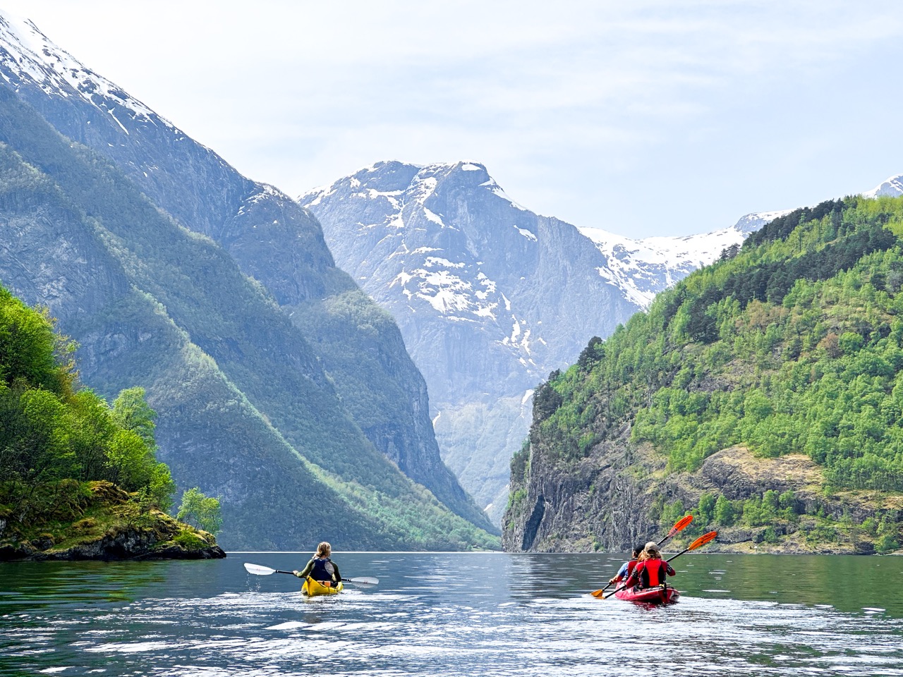 Kayakers surrounded by mountains of Naeroyfjord
