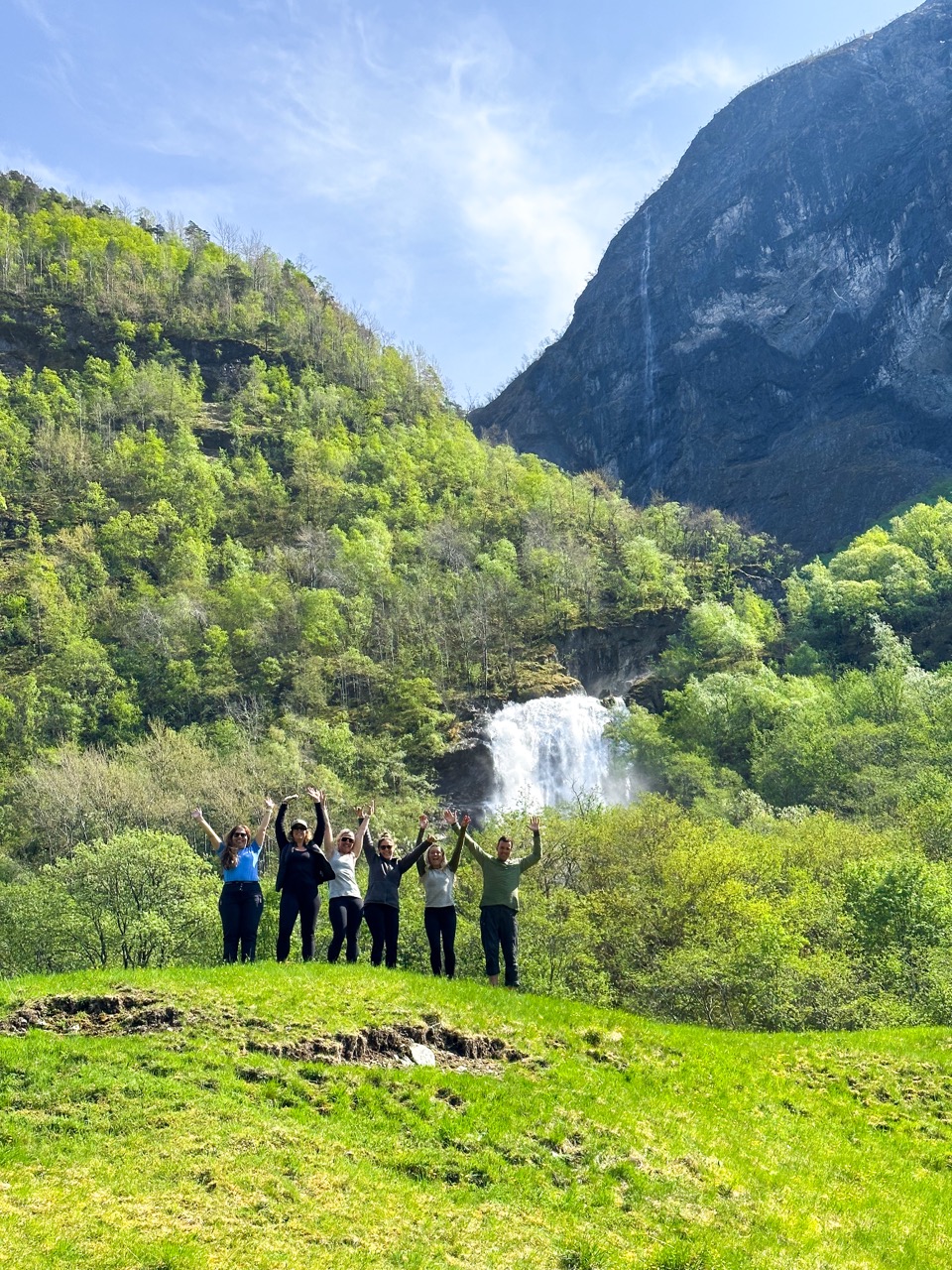 A group of hikers in from of the waterfalls in Odnes