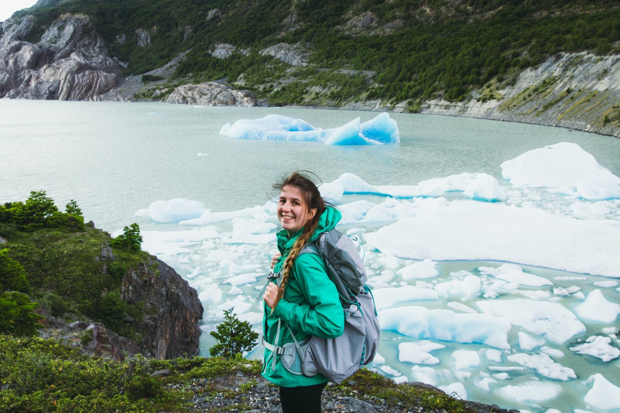 A woman trekker smiling beside floating ice formations in Torres del Paine, Chile.