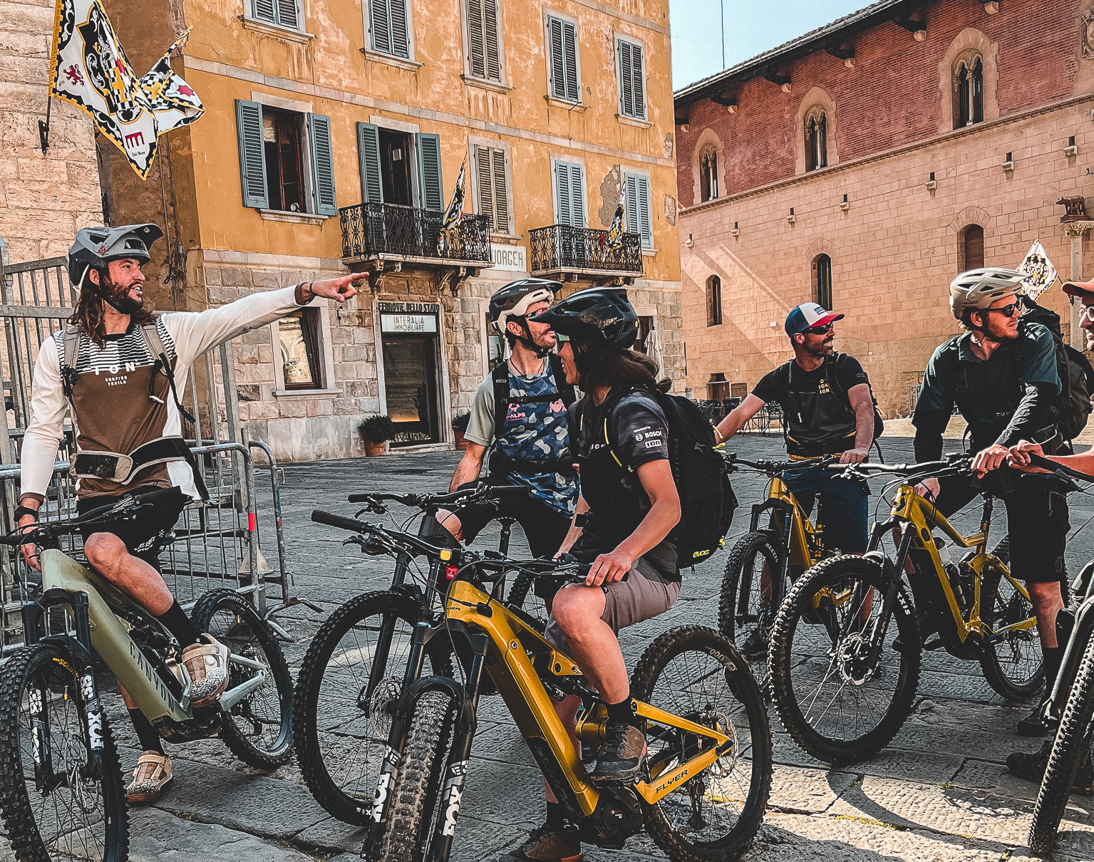 A group of e-mountain bikers and their guide gathered in a typical town square in Tuscany, Italy.
