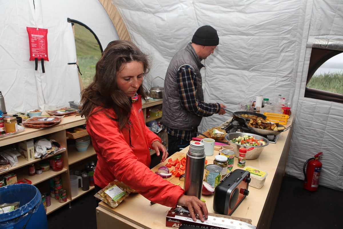 Two people preparing food in a campsite kitchen