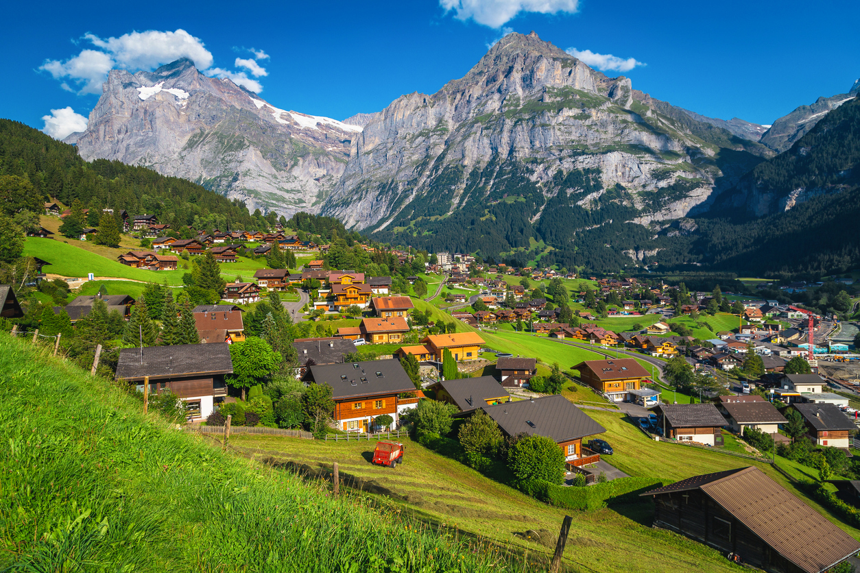 The resort town of Grindelwald in the Swiss Alps, with wooden houses, framed by lofty peaks.