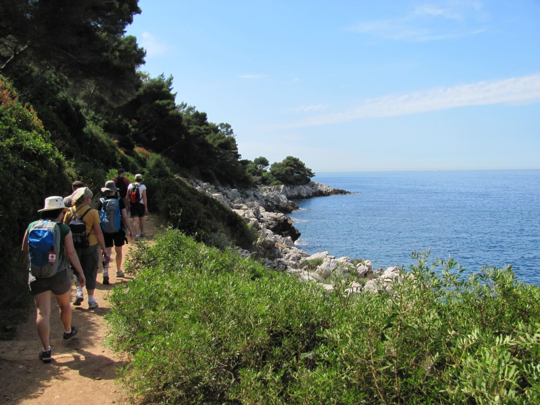 Hikers walking along a shoreline in Provence