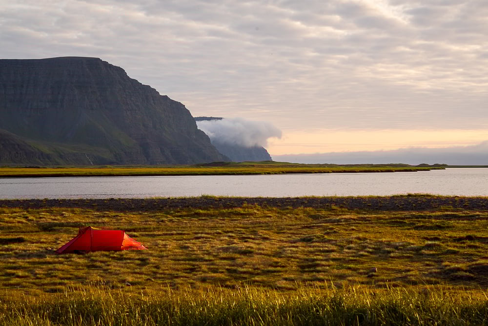 A red tent in a bay in the Hornstrandir Nature Reserve, Iceland.