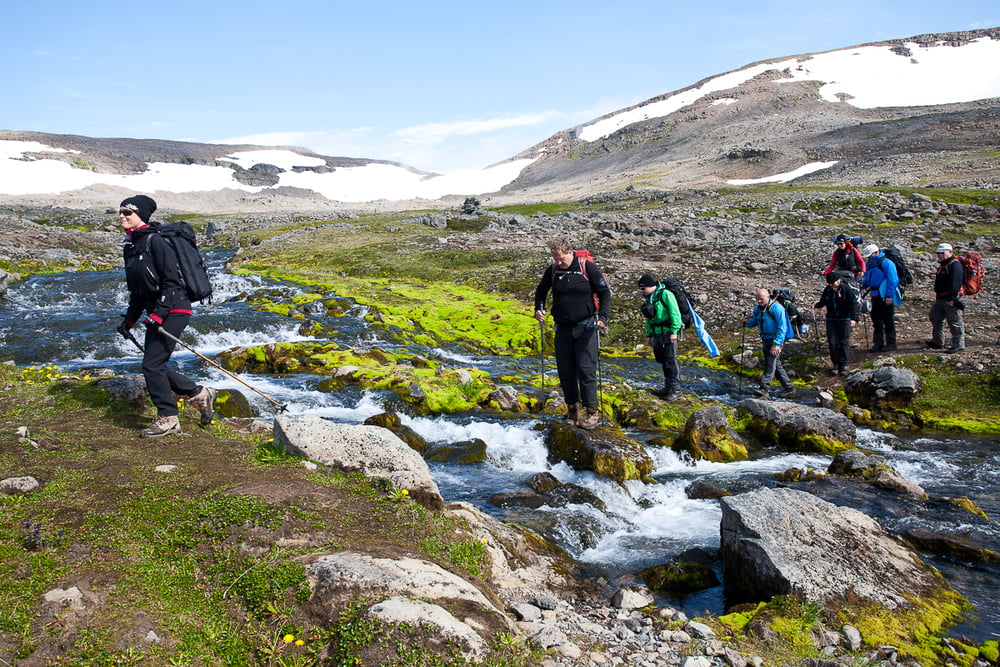 Backpackers crossing a river in Hornstrandir Nature Reserve.
