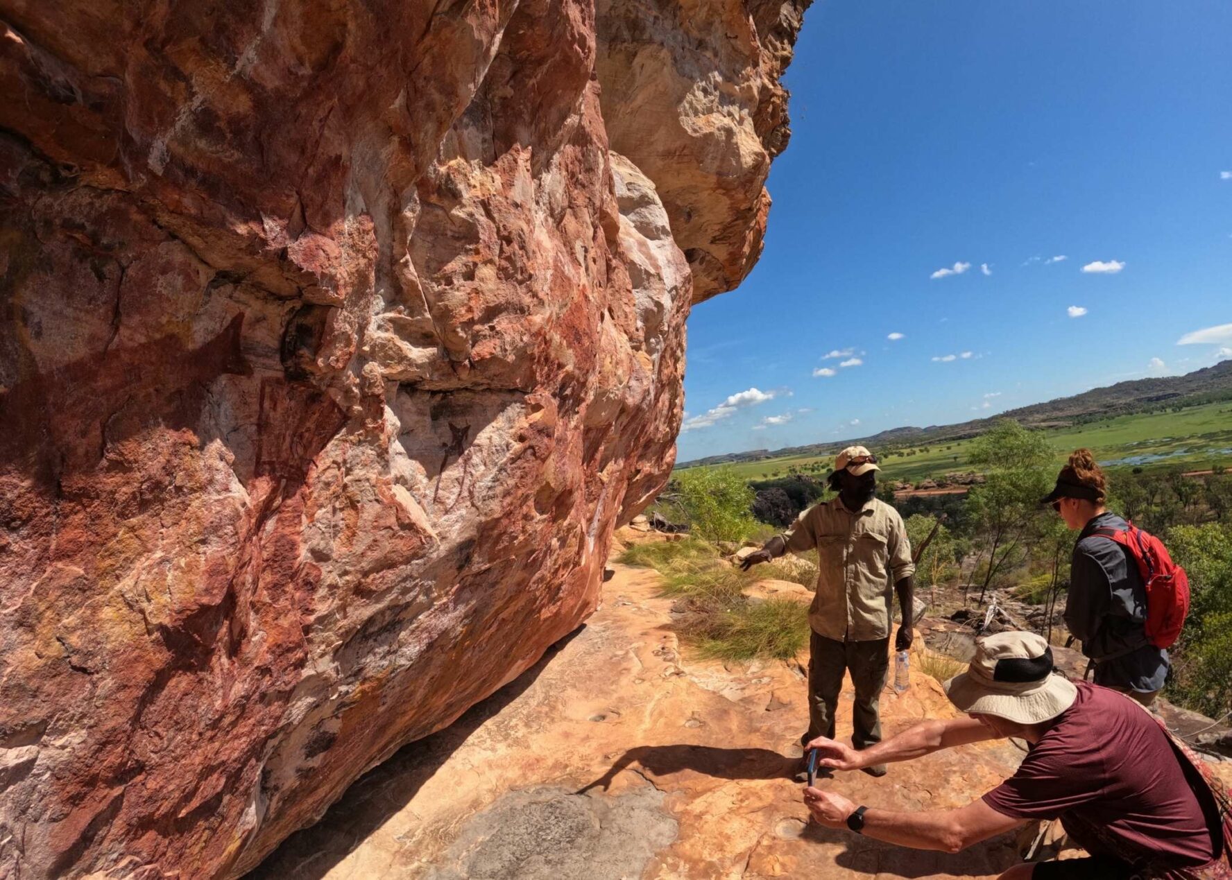 Hikers and their guide looking at ancient Aboriginal rock art in the Kakadu National Park.