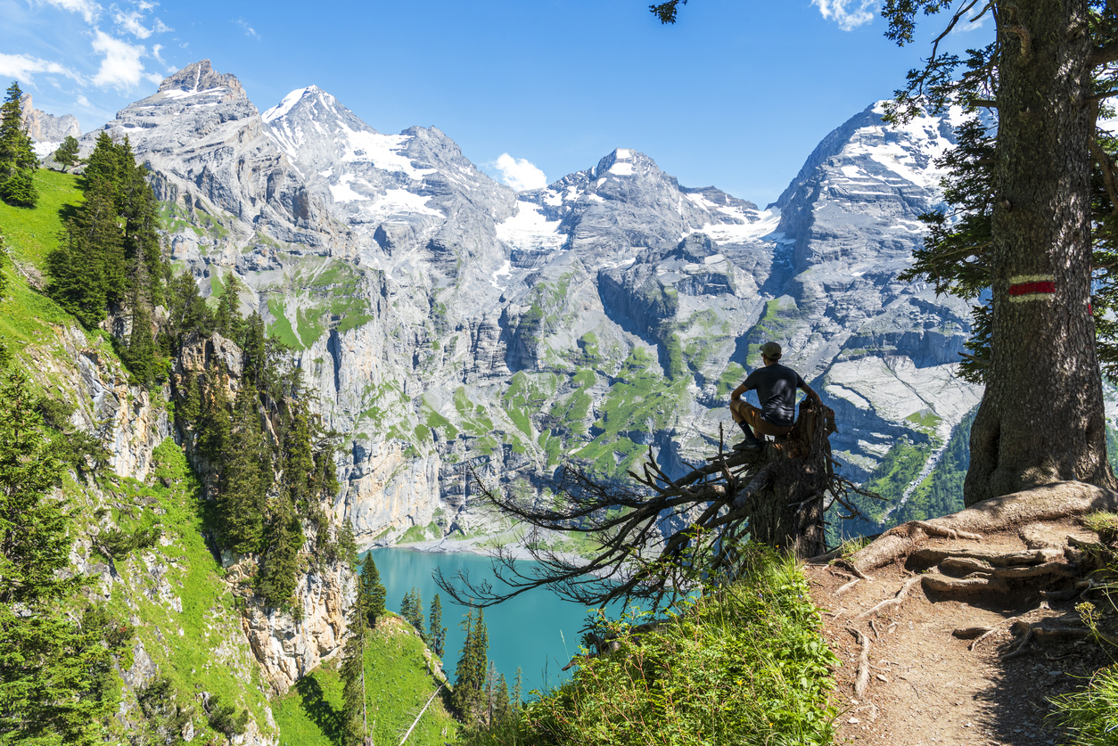 A hiker at a highpoint observing the Oeschinen lake in the Swiss Alps.