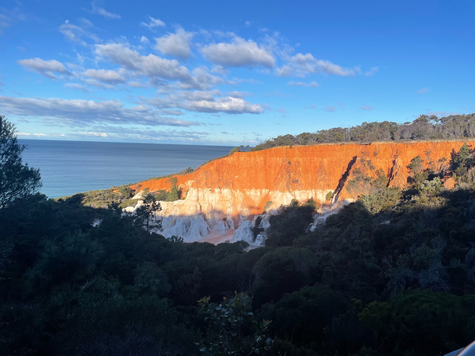 Red cliff along Australia's Sapphire Coast, seen from a distance.