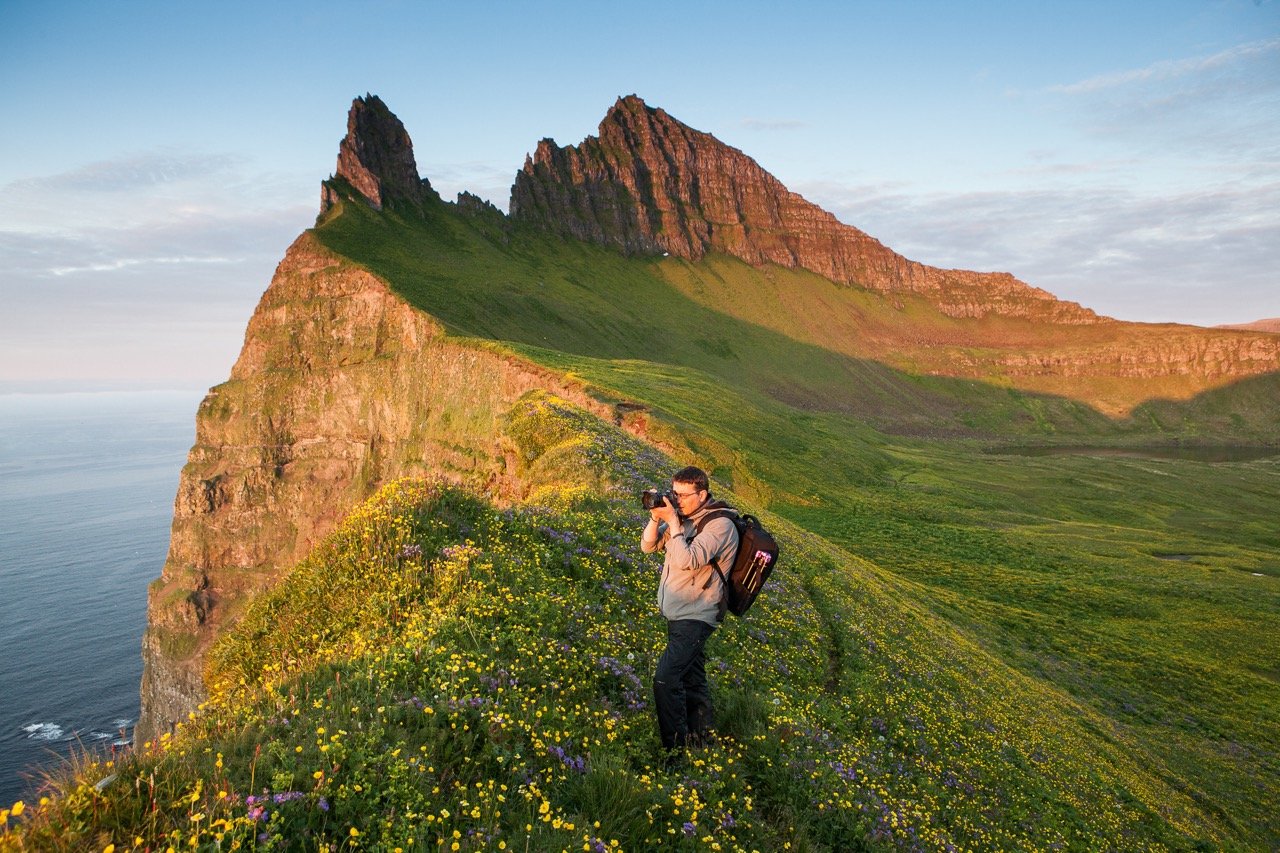 A woman taking photos from a beautiful green cliff