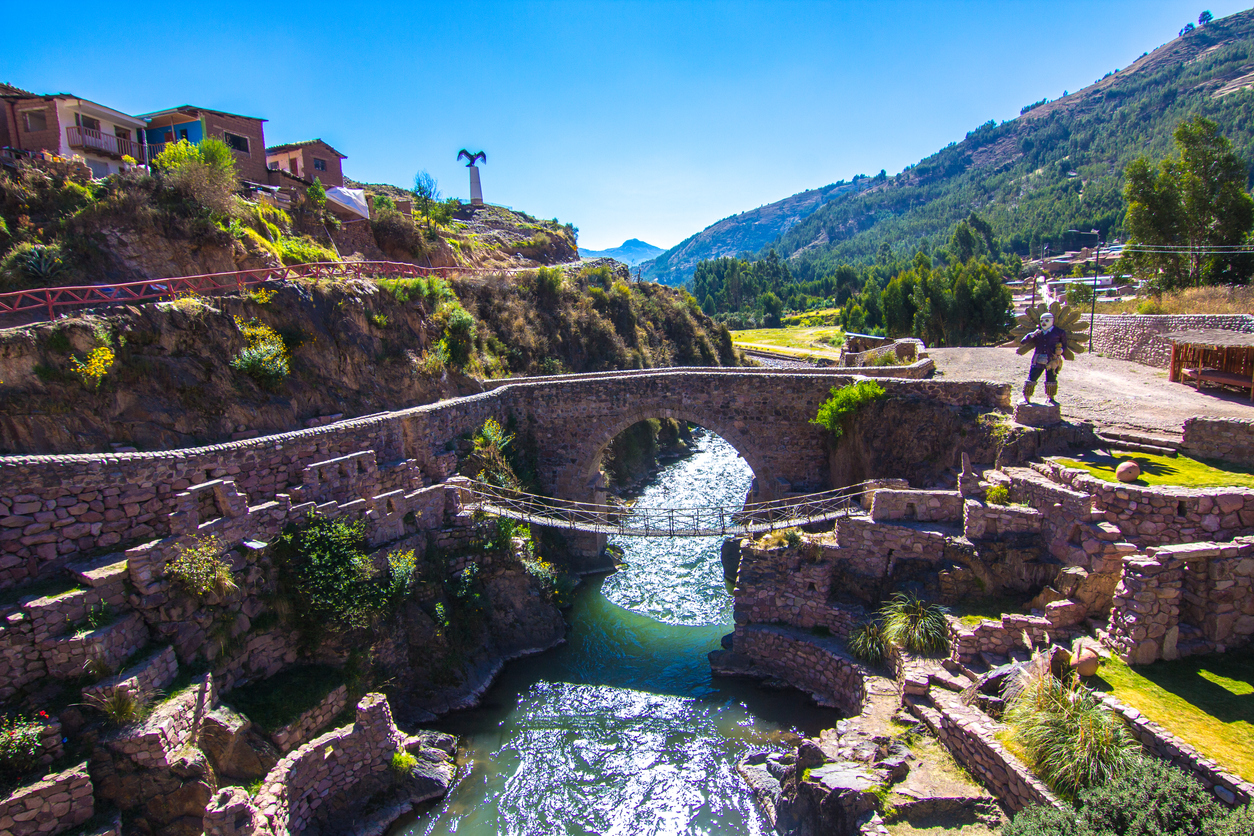 Checacupe village with a river and a stone bridge.