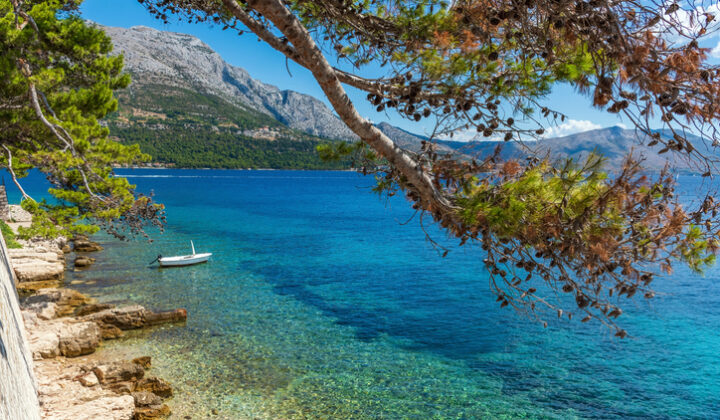 Small boat moored by rocky beach in picturesque old Korcula town on Korcula island, Croatia