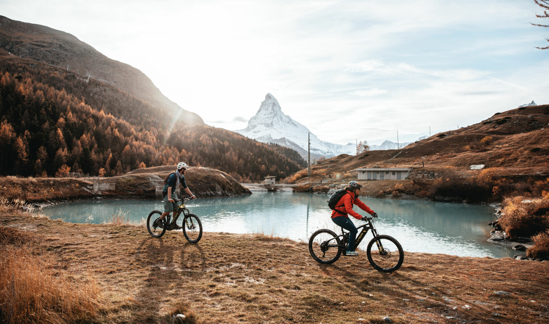 Cyclists riding next to an Alpine like with stunning views of the Matterhorn.
