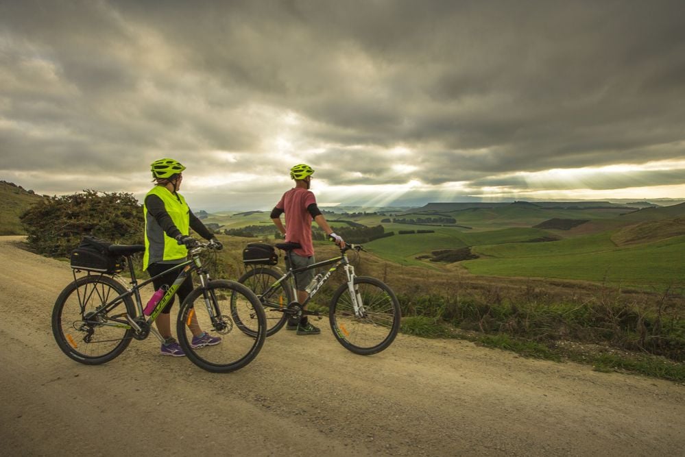 Cyclists looking at a valley in New Zealand while on the Alps to Ocean Trail.