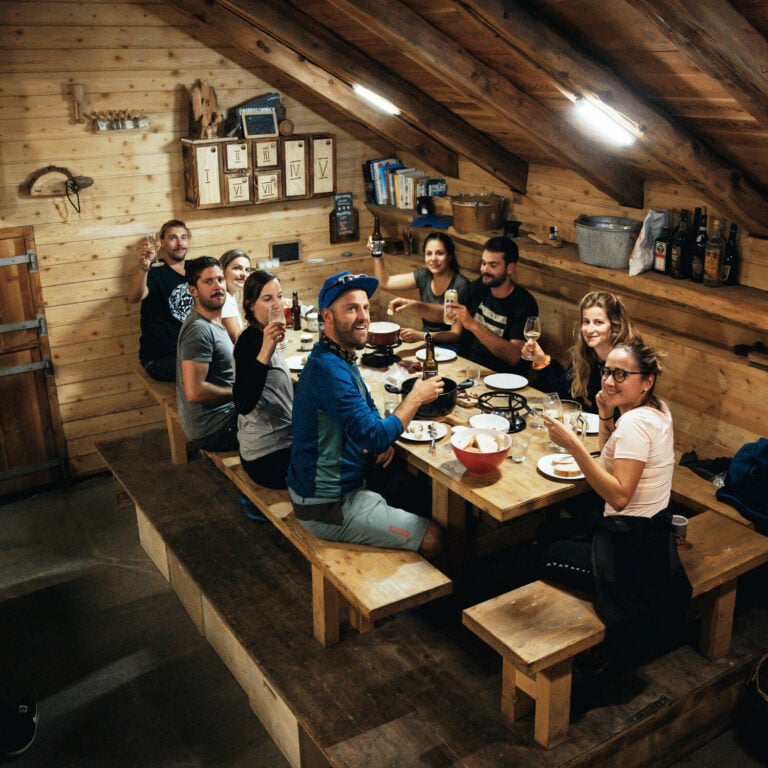 Haute Route e-mountain bikers enjoying dinner in a cozy hut.