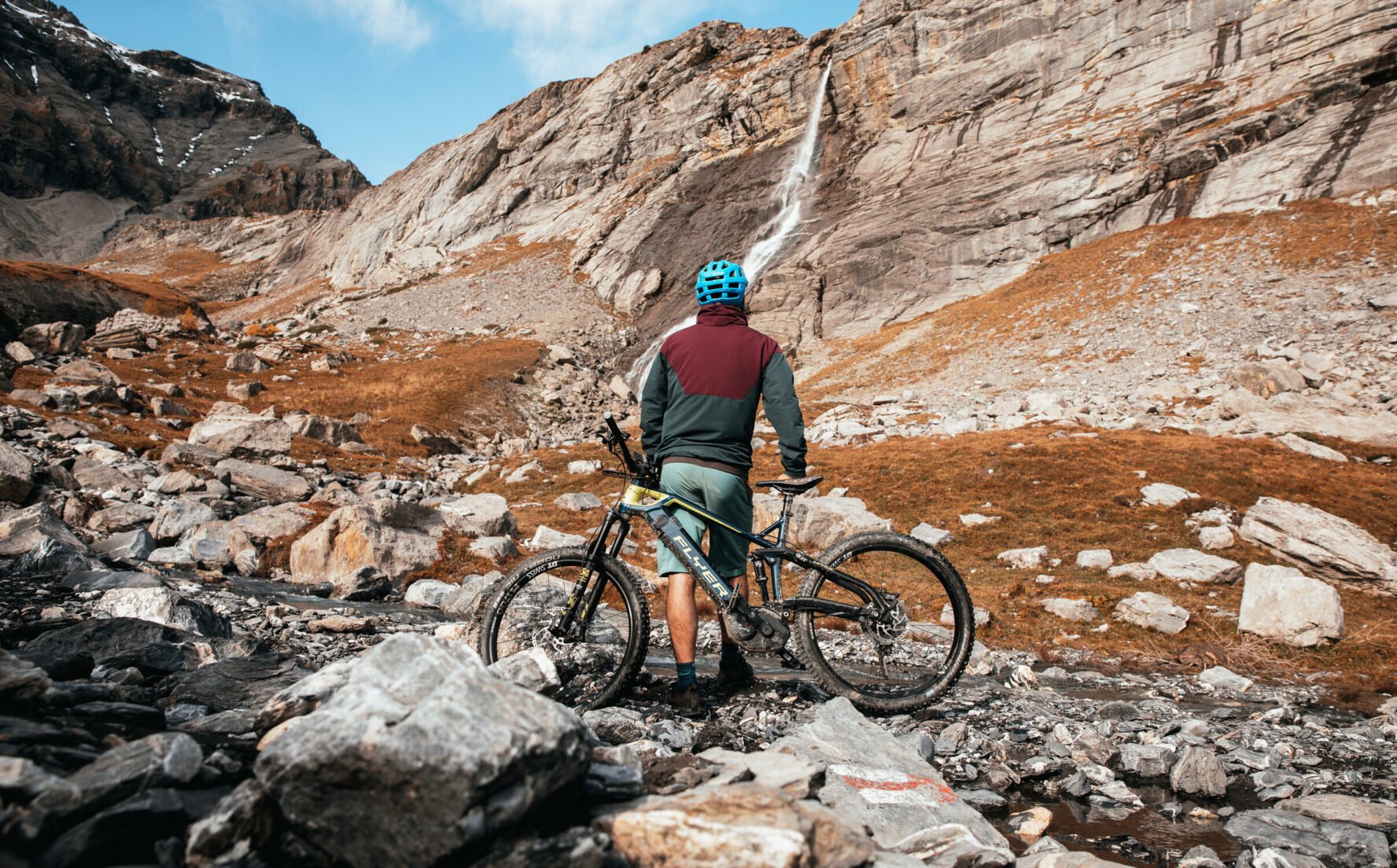 E-mountain biker looking at a high waterfall in the Swiss Alps.