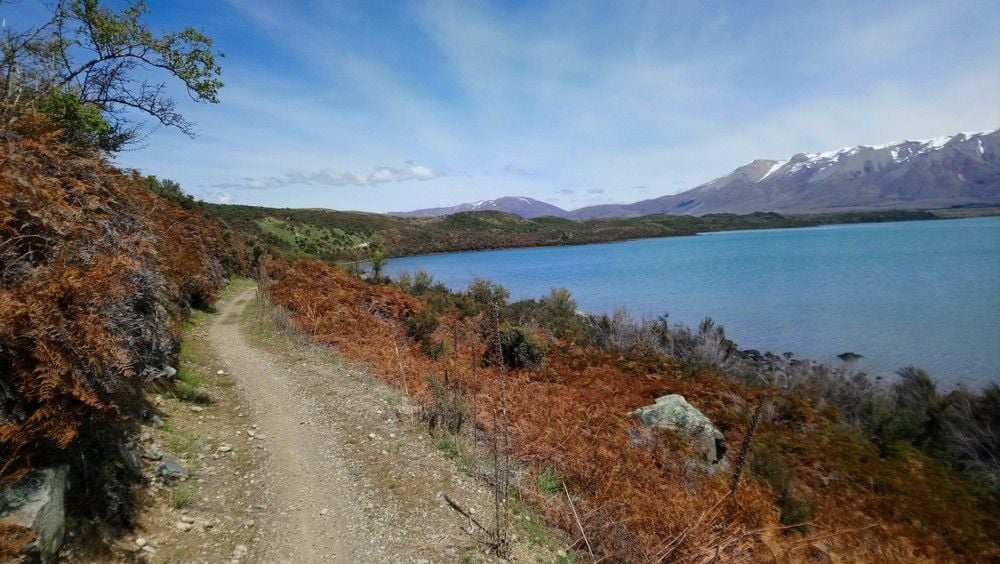 A narrow gravel road by the lake, part of the Alps 2 Ocean Cycle Trail.