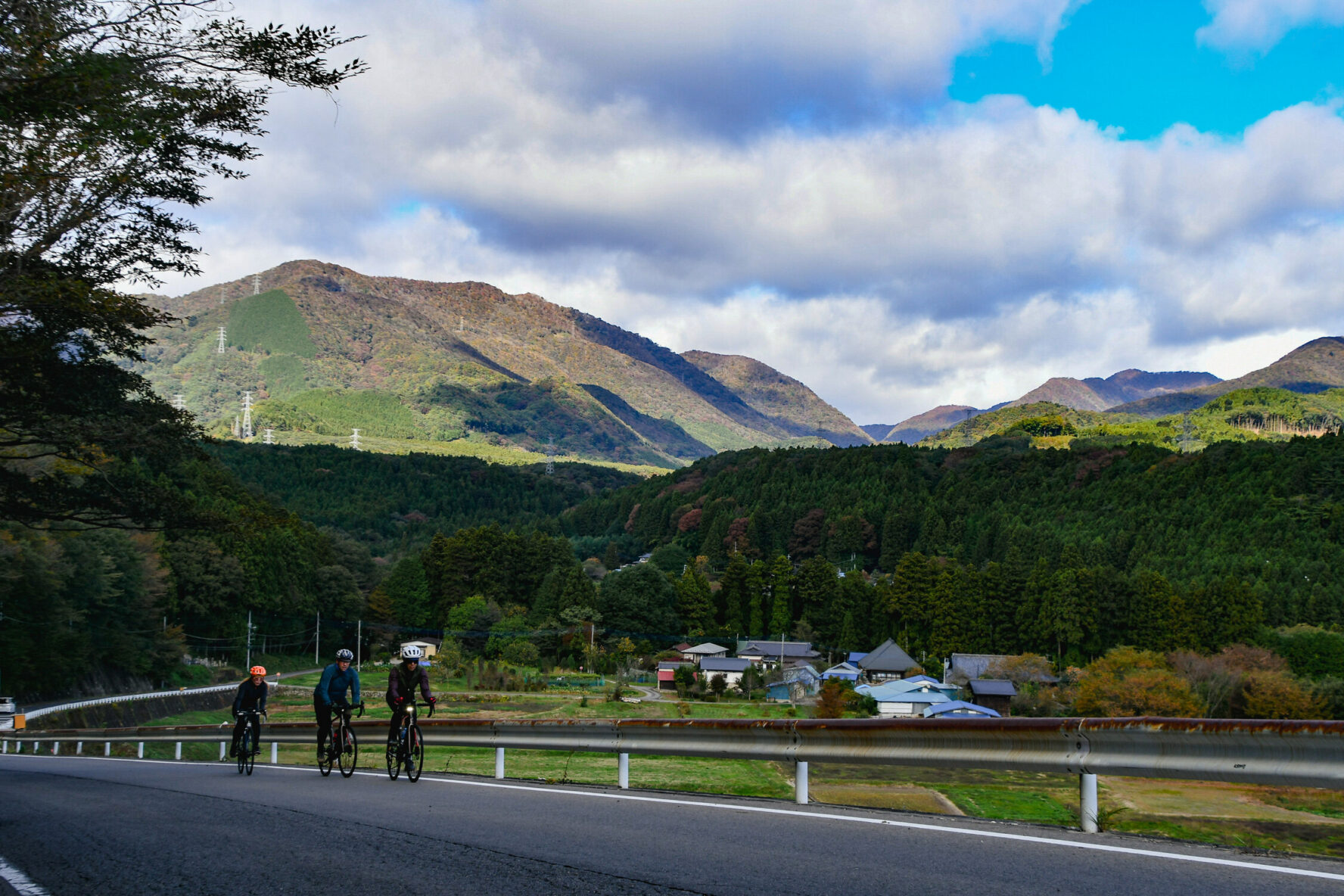 Cyclists riding on a road passing through the Japanese countryside in Tochigi.