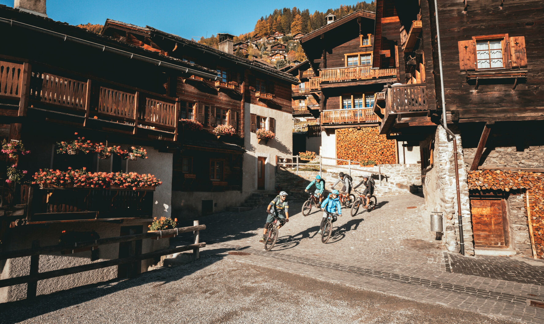 E-mountain bikers riding through a Swiss village in the Alps.