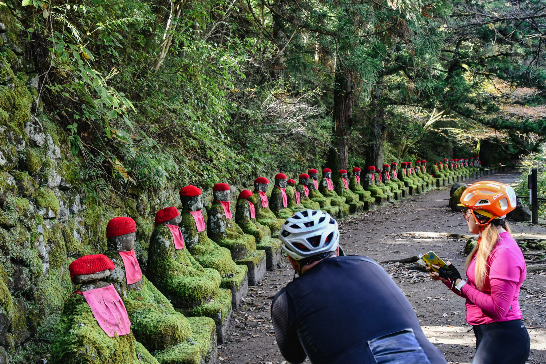 Cyclists looking at ancient Japanese stone statutes in Nikko.