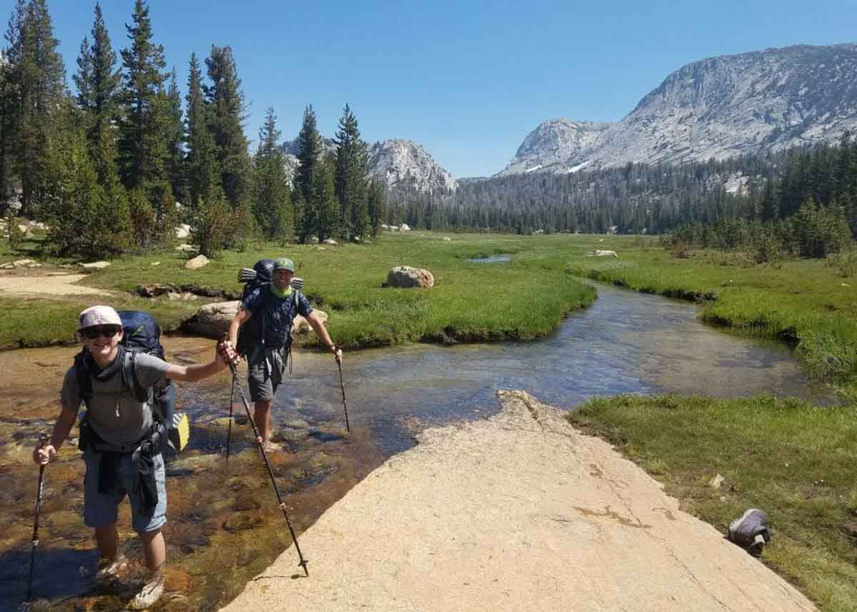 Hikers crossing a small river in Yosemite.