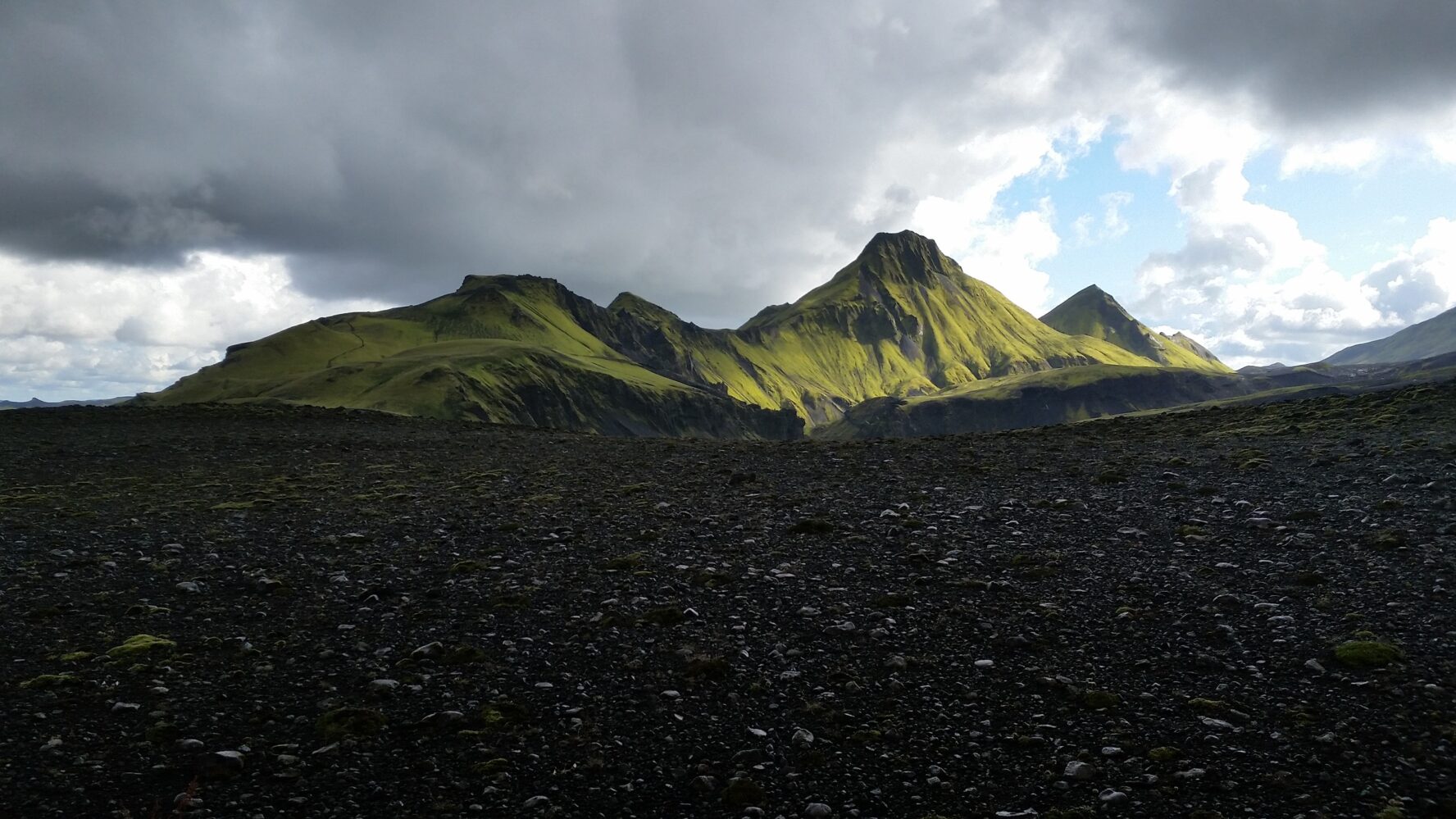 Mossy Uxatindar mountain looming above a jet-black expanse, Icelandic Highlands.
