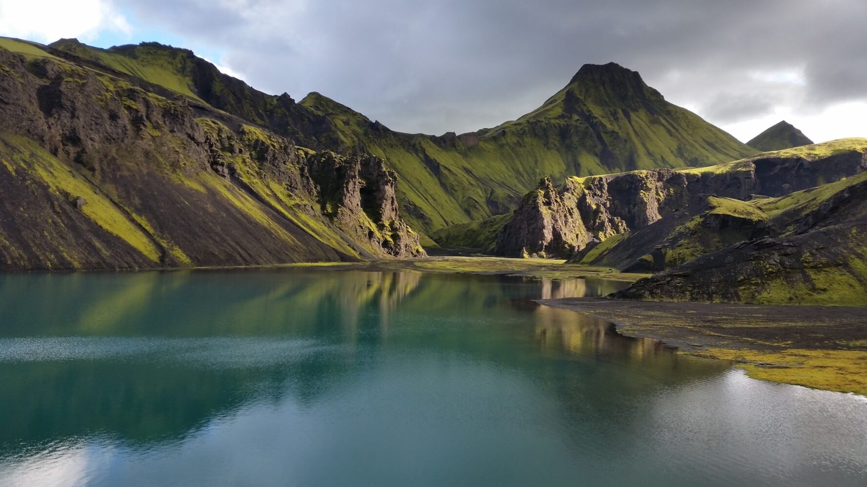 Uxatindar mountain, covered in green moss, beside a lake, in the Icelandic Highlands.